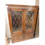 OAK FRAMED BOOKCASE WITH TWO LEADED AND GLAZED DOORS OVER TWO LINENFOLD FRONTED DOORS