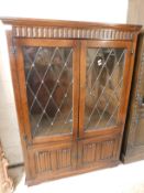 OAK FRAMED BOOKCASE WITH TWO LEADED AND GLAZED DOORS OVER TWO LINENFOLD FRONTED DOORS