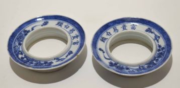 Two Chinese porcelain cup or beaker holders with a blue and white design and Chinese script around