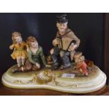 Large Capo di Monte porcelain group of a beggar musician with children on a shaped base, 33cm long