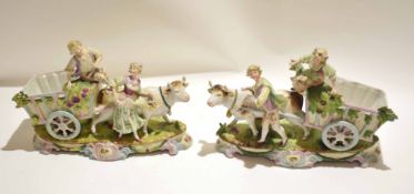 Pair of Continental porcelain figures of cows being led by a boy and a girl with carts, standing