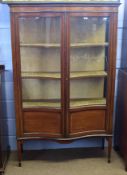 Edwardian mahogany china display cabinet, of serpentine form with glazed front and sides enclosing