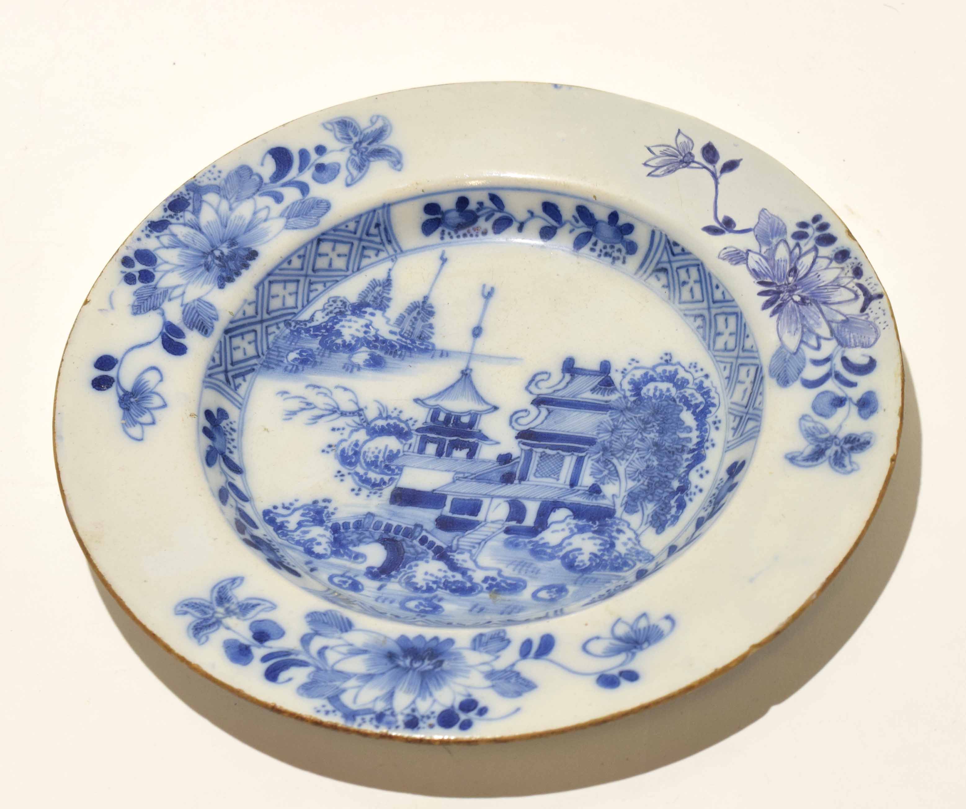 English Delft plate decorated with a pagoda within a border of floral sprays, 23cm diam