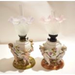 Pair of late 19th century Continental porcelain oil lamps, the lamp reservoirs supported by three