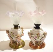 Pair of late 19th century Continental porcelain oil lamps, the lamp reservoirs supported by three