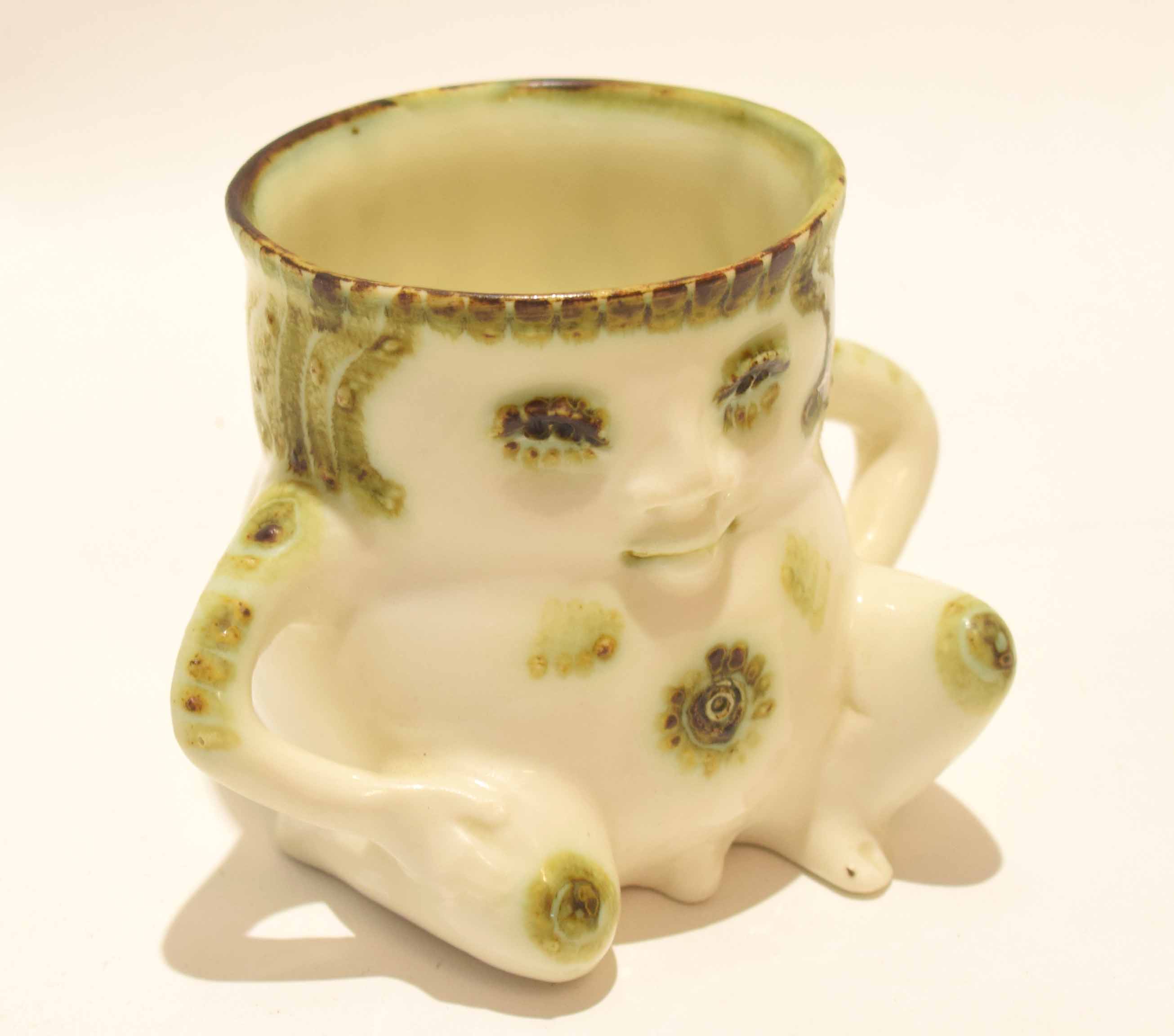 Pottery mug modelled with a face and the handles modelled as arms