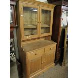 WAXED PINE BOOKCASE WITH TWO GLAZED DOORS, THE BASE WITH TWO DRAWERS OVER TWO PANELLED CUPBOARD
