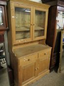 WAXED PINE BOOKCASE WITH TWO GLAZED DOORS, THE BASE WITH TWO DRAWERS OVER TWO PANELLED CUPBOARD