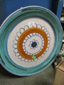 LARGE POOLE TYPE CHARGER WITH A CIRCULAR AND LOOPED DESIGN TO THE CENTRE WITHIN A GREEN WASH BORDER,