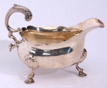 George II large sauce boat with card cut rim, leaf clad flying scroll handle and supported on