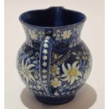 Thune Pottery jug, the blue ground decorated in white with floral sprays, 12cm high