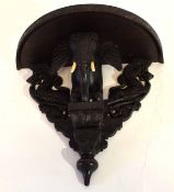 Anglo-Indian ebonised demi-lune shaped wall bracket, the support carved in the form of the head
