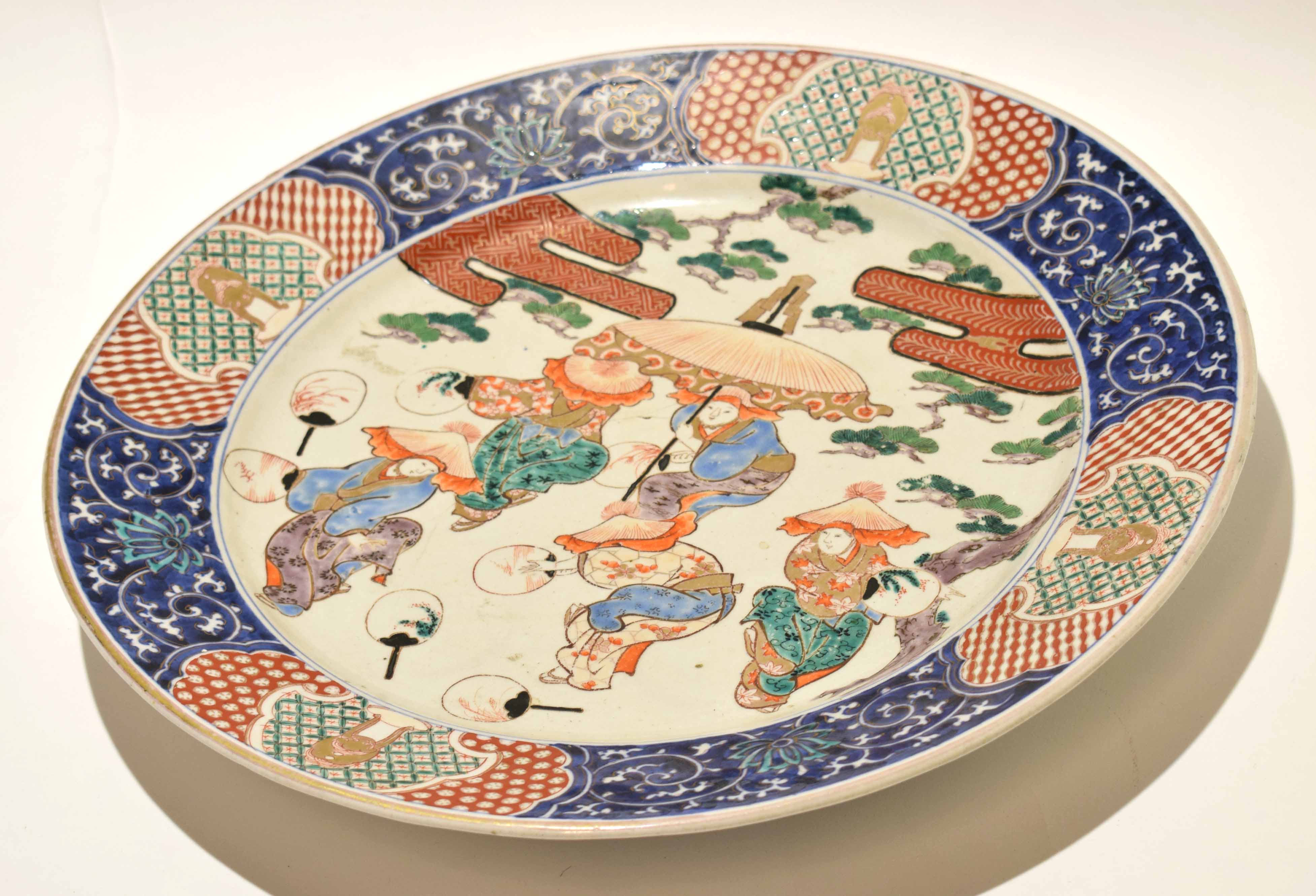 Late 19th century Japanese porcelain charger, decorated with figures at various pursuits within an