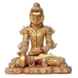 Wooden carving of a Buddha in typical pose, the wood with painted gilt decoration and inlaid glass