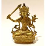 Gilt metal model of a Buddhistic deity in classic pose with inscription to rear, 21cm high