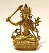 Gilt metal model of a Buddhistic deity in classic pose with inscription to rear, 21cm high