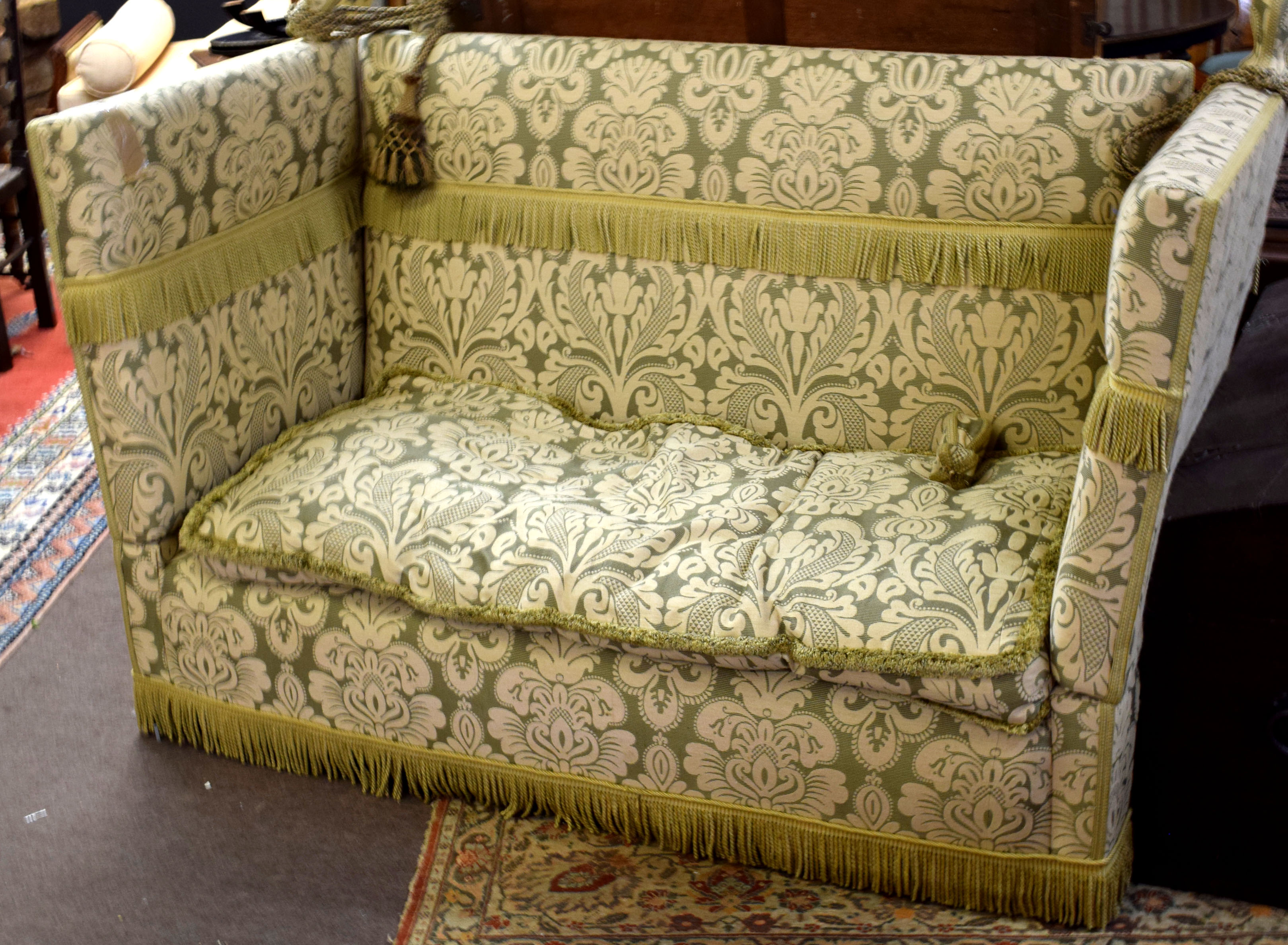 Early 20th century Knole sofa, of typical drop ends and rope ties to corners, upholstered in green