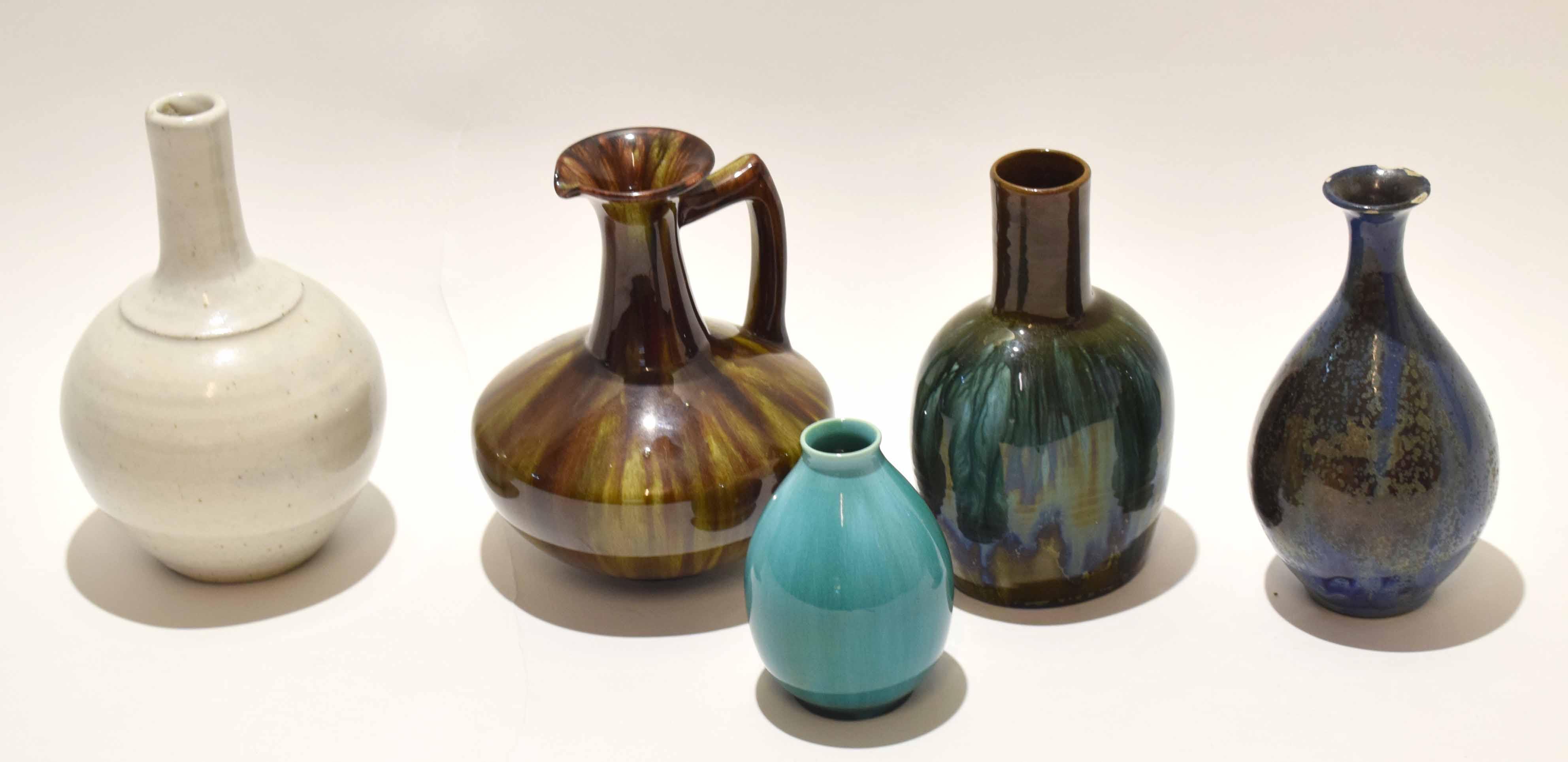 Group of high fired pottery wares comprising a Pilkington green glaze vase, two further glazed vases