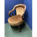 A barbers chair, with mahogany rounded back, and on turned legs to castors