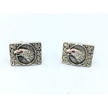 Pair of silver cufflinks depicting a bird of prey with ruby eyes