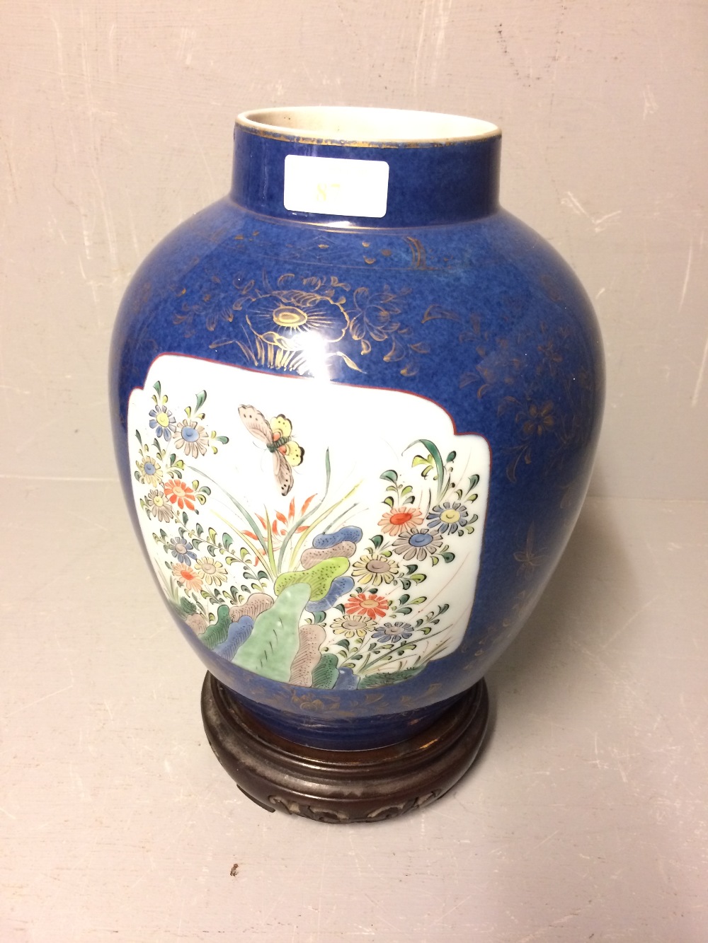 Blue & gilt decorated Chinese jar on wooden stand. The vase with 2 panels decorated with flowers &