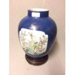 Blue & gilt decorated Chinese jar on wooden stand. The vase with 2 panels decorated with flowers &