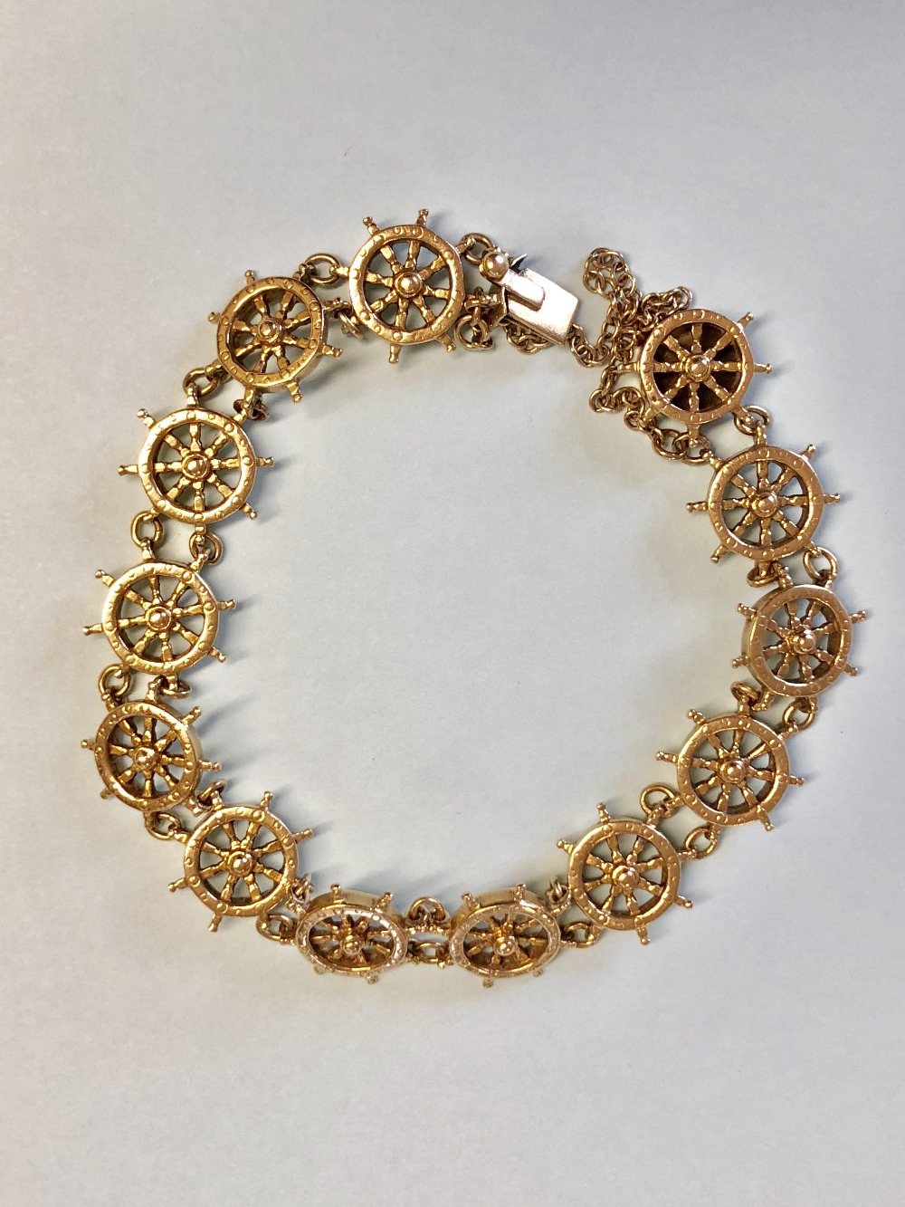 18ct gold nautical bracelet of 13 linked ships wheels by Bernard Taylor & Rebecca retailed by Benzie