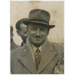 Don Bradman. Original mono press photograph of Bradman, head and shoulders smiling, having arrived