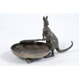 'For the Ashes'. A silver plated [?] circular ashtray cast with a figure of a kangaroo holding a