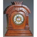 A late 19th century oak cased mantel clock having an enamelled chapter ring with Roman numerals