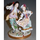 A Sitzendorf porcelain figure group of male and female in standing pose, in period costume, having