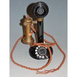 An early 20th century bakelite and brass stick telephone