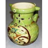 A Devonware art pottery mottoware puzzle jug, on a green ground, with incised fish decoration,
