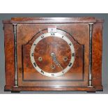 An Art Deco walnut cased mantel clock, having a silvered chapter ring with Roman numerals and