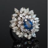 A sapphire and diamond cluster ring, the oval sapphire, approx. 9.3 x 6.3mm, in a four claw mount