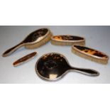 A George V silver mounted and tortoiseshell backed hand mirror together with a matching brush and