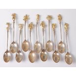 A set of eleven white metal and gilt metal teaspoons, the terminals each cast with signs of the