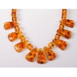 An amber necklace, the half set tapered triangular amber beads, 35mm long, interspaced and