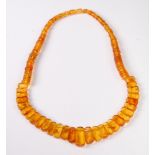 An amber necklace, the half set graduated rectangular amber beads followed by amber disc beads, 50cm