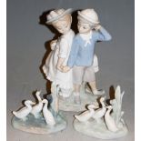 A Lladro figure group of a boy and girl in standing pose holding hands, printed mark verso, height
