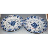 A pair of 18th century Delft blue and white plates, each decorated with an urn issuing flowers