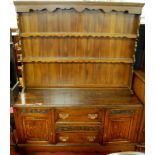 A 1930s relief carved oak dresser, having two-tier open plate rack over base fitted with twin