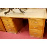 An early 20th century light oak kneehole writing desk, having twin upper slides each over three