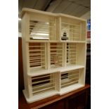 A contemporary white painted three division wall mounted plate rack, w.85.5cm