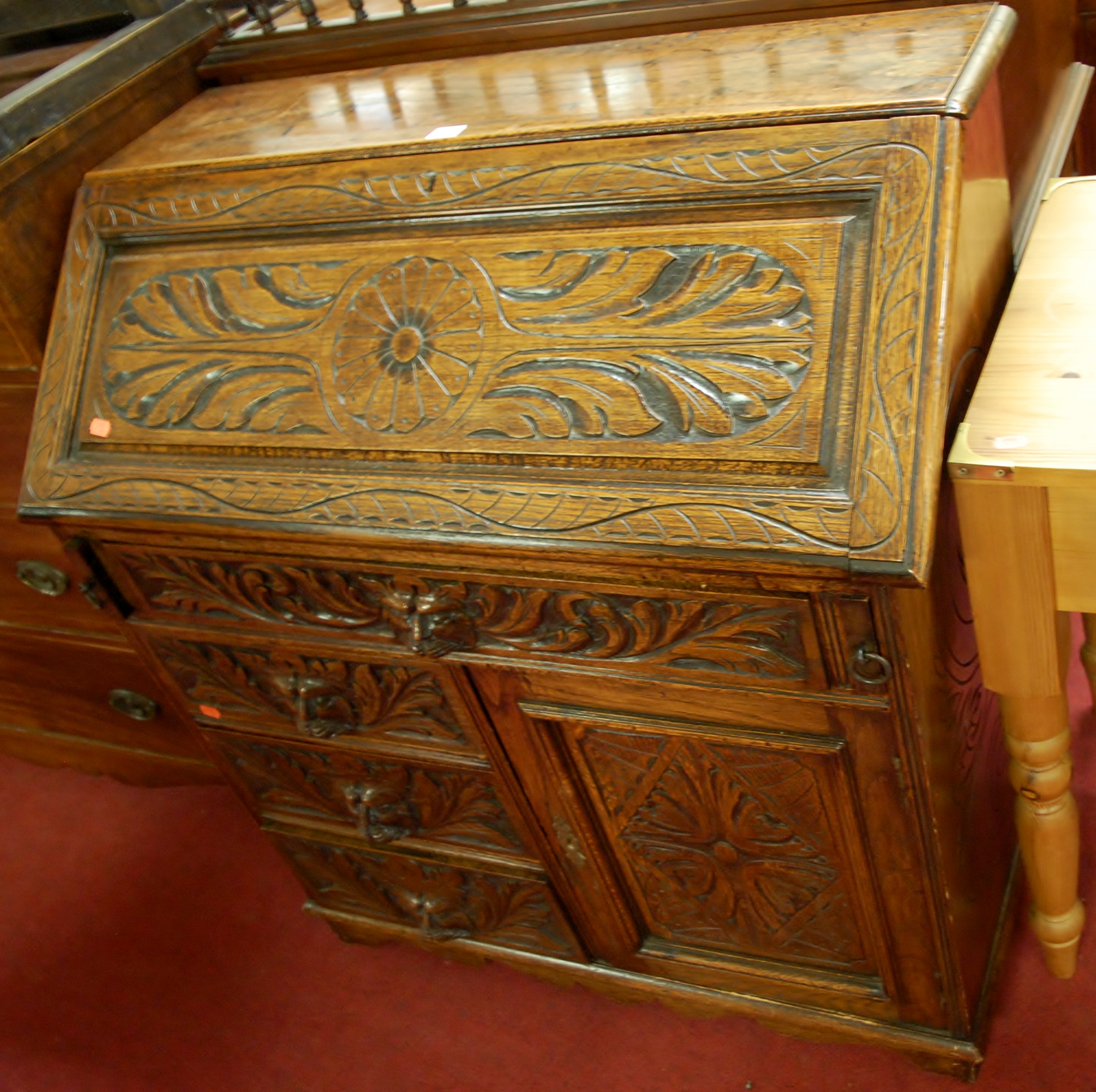 A late 19th century heavily carved oak slopefront writing bureau, having four Green Man mask
