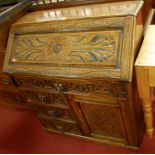 A late 19th century heavily carved oak slopefront writing bureau, having four Green Man mask