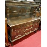 An early 20th century Jacobean moulded oak ledgeback sideboard, the raised and panelled