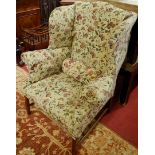 A 19th century mahogany framed and floral upholstered wingback armchair, raised on slightly tapering