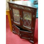 A contemporary Stanley Wood moulded oak and lead glazed low four door corner cupboard