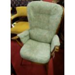 A contemporary Ercol mid elm stickback armchair, having green floral upholstered cushion back and